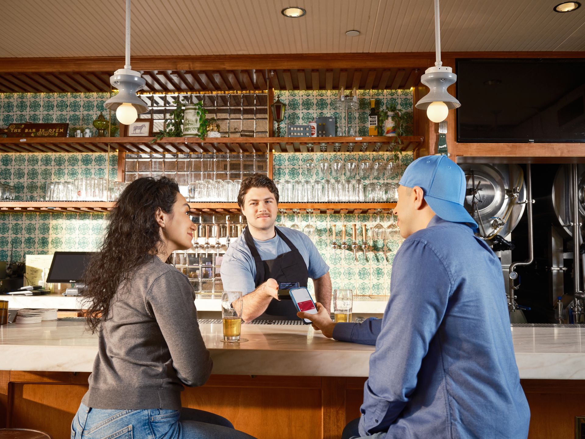 Bartender completing a mobile payment for guests at a modern bar